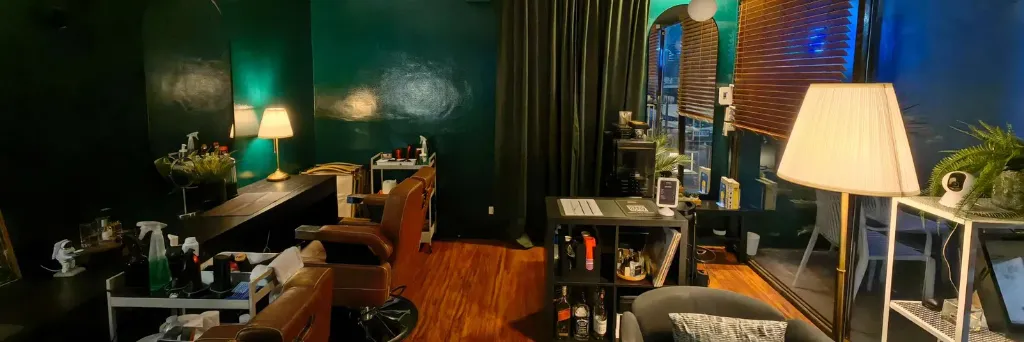 Wilsons Midnight Barbers interior in Dasmariñas, Cavite featuring tall evergreen walls, redwood floors, and rustic orange barber chairs under ambient late-night lighting